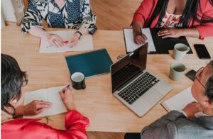 women sitting around a table working at a computer